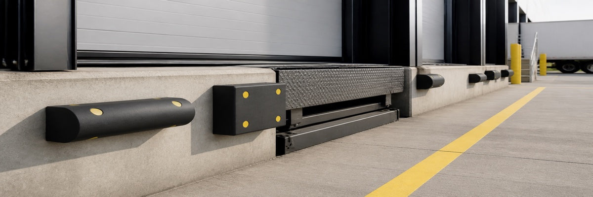 Black D-shaped and square rubber dock bumpers installed on a modern concrete loading bay